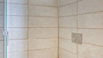 Un baño con azulejos color beige, un inodoro blanco y una ventana.