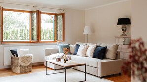 Un salon moderne avec un canapé, une table basse et une fenêtre donnant sur un paysage verdoyant.