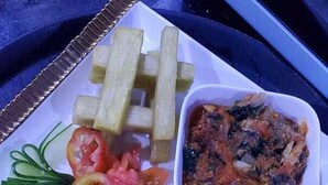 Un plato con papas fritas, rodajas de tomate y un recipiente pequeño con salsa, sobre una mesa.