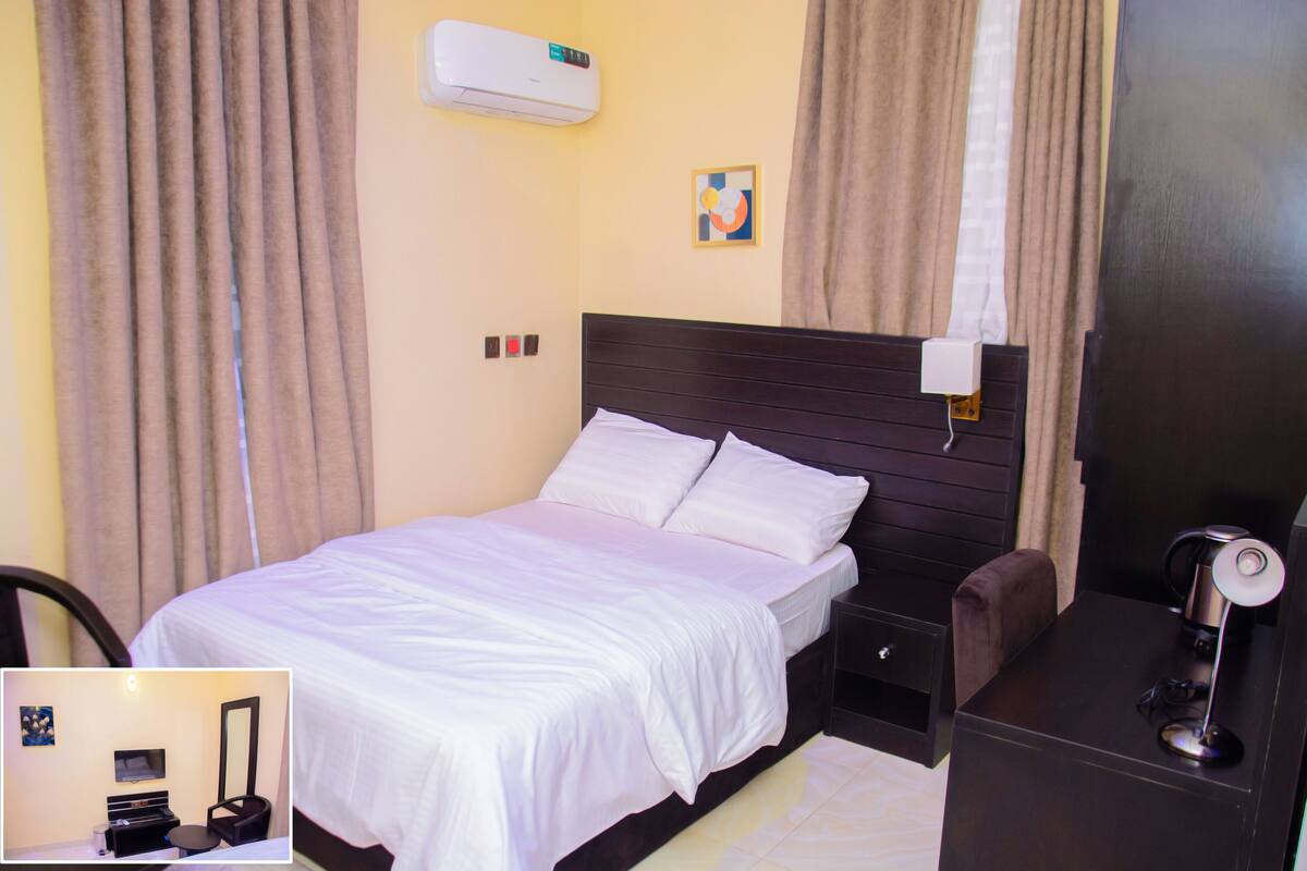 Une chambre d’hôtel équipée d’un lit, d’un bureau, d’une chaise, d’une télévision et d’un appareil de climatisation.