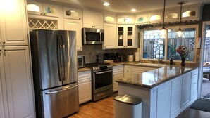 Una cocina moderna con electrodomésticos de acero inoxidable, armarios blancos y una isla central.
