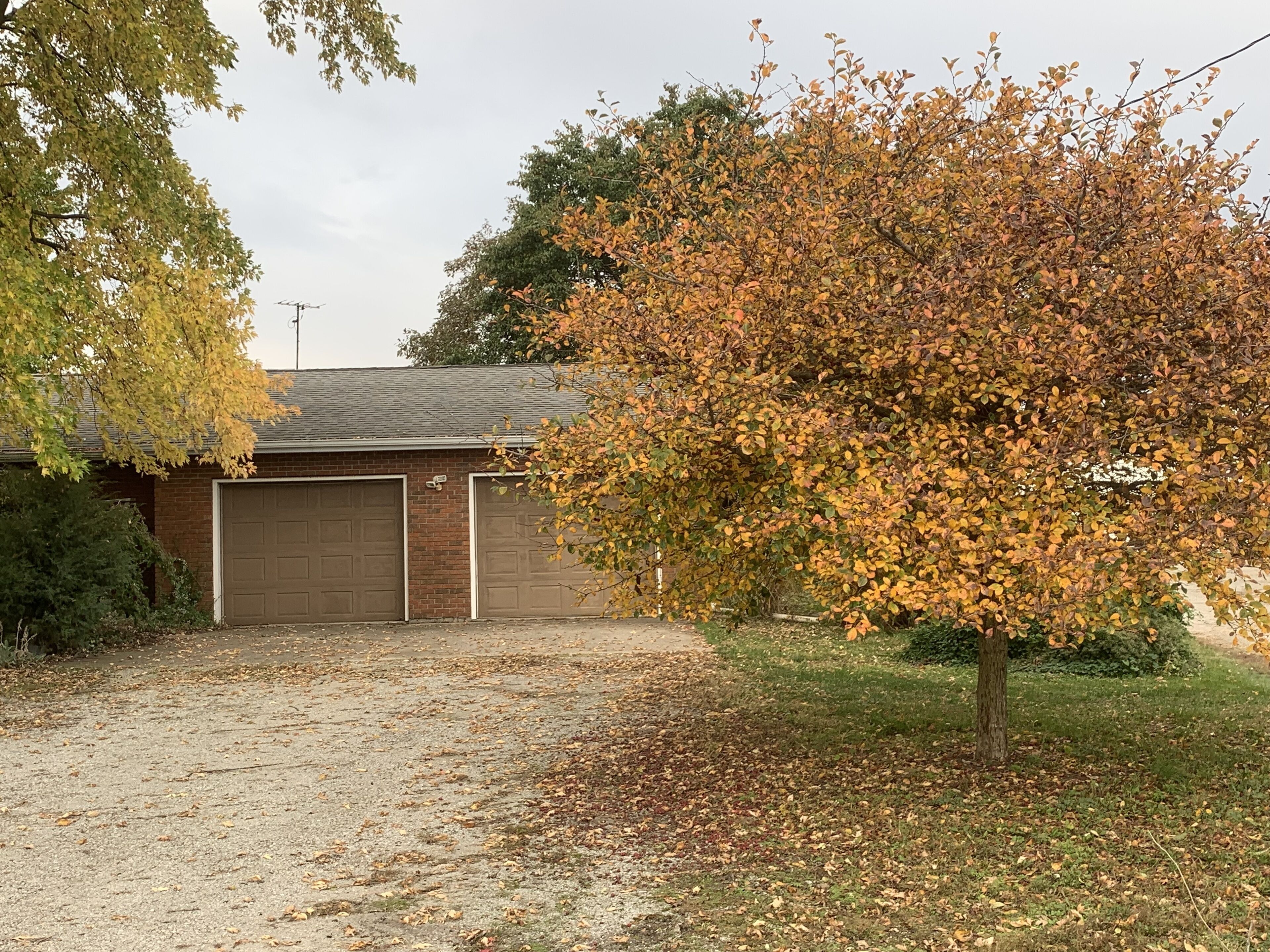 A two-car garage attached to a brick building with a gravel driveway.