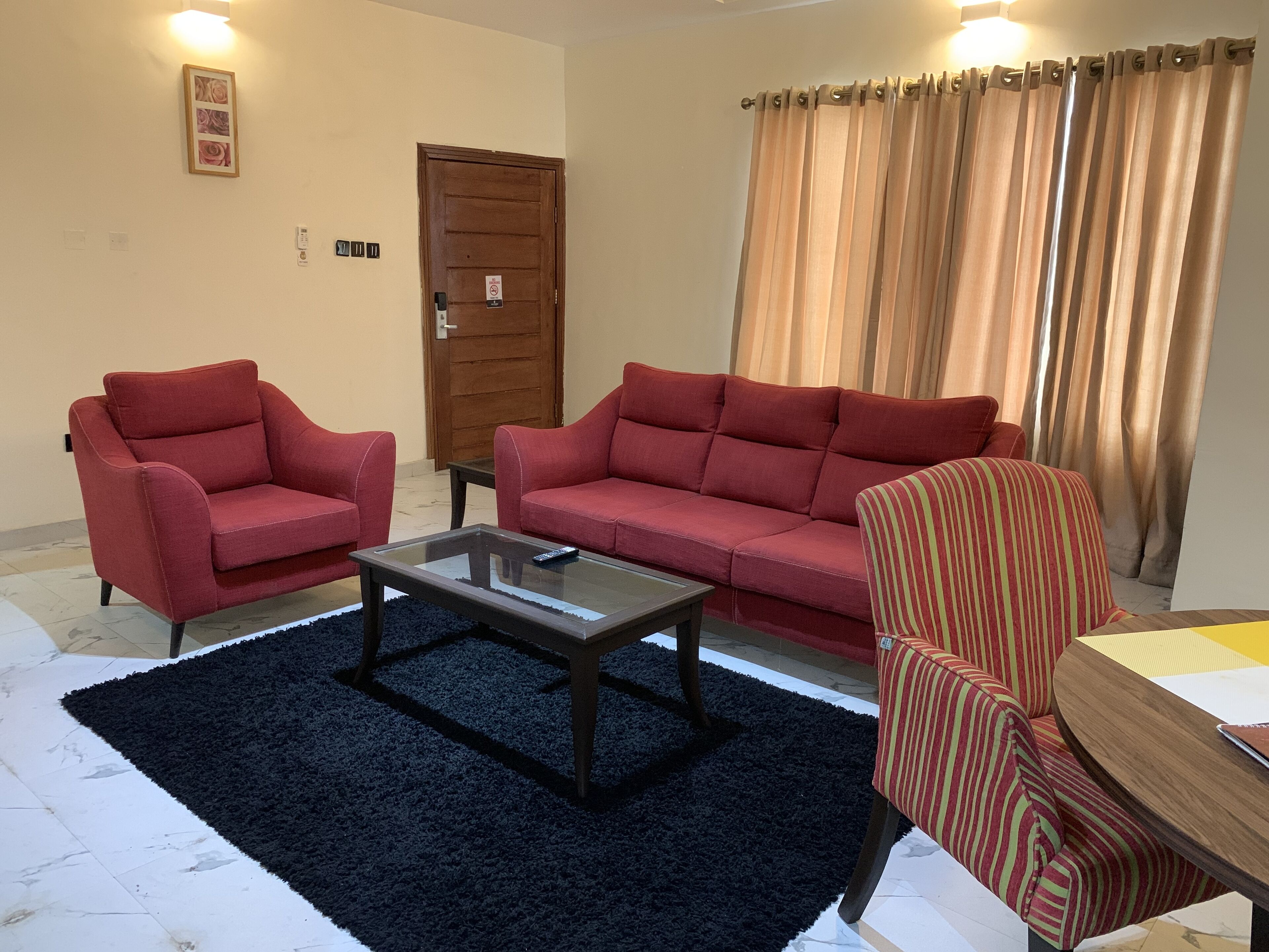 A living room with two red sofas, a glass coffee table, a striped armchair, and a dark rug.