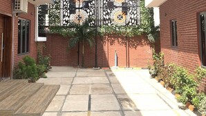 A courtyard with a decorative metal gate, brick walls, and potted plants. - Old English Torf Apartment (Owerri)
