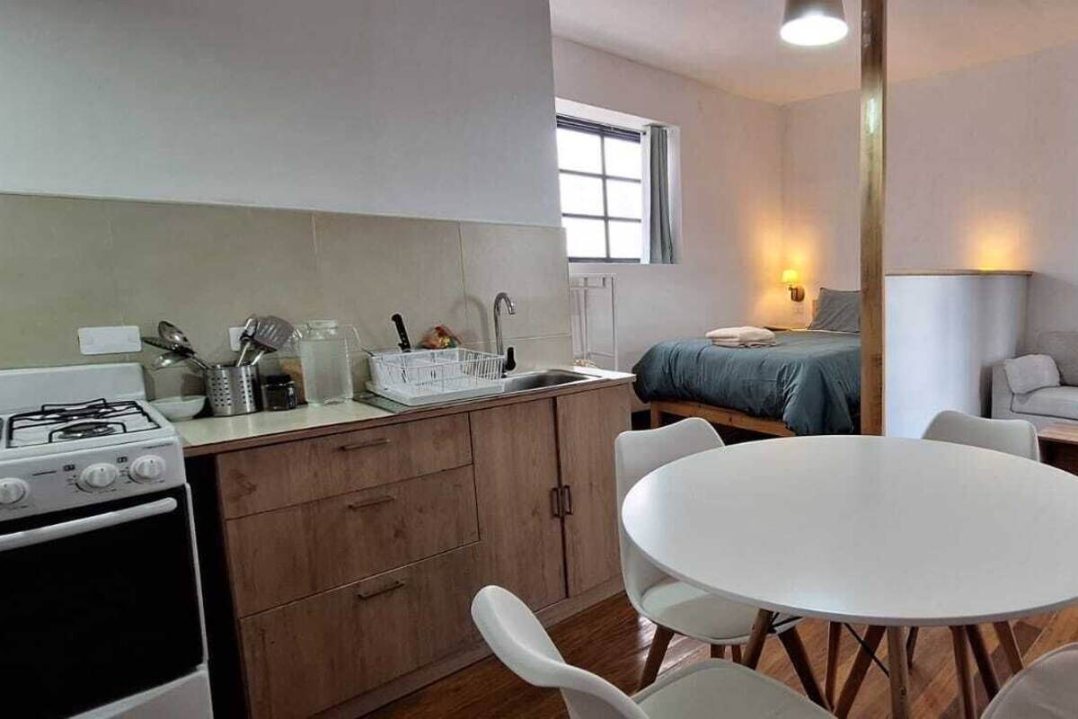 A compact living space with a kitchenette, a dining table, and a sofa.