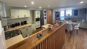 Une cuisine moderne avec un plan de travail en bois, des armoires blanches et un coin repas comprenant un canapé et des chaises.