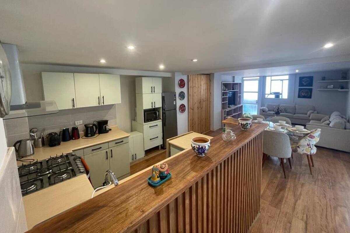 A modern kitchen with a wooden countertop, white cabinets, and a dining area with a sofa and chairs.