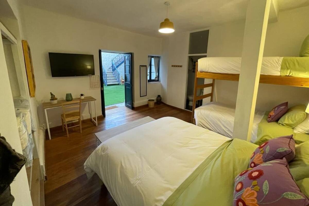 A bedroom with a bunk bed, a desk, and a television.
