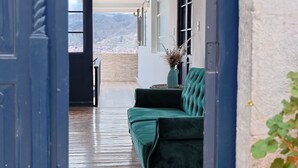 Una habitación con un sofá verde, una planta en maceta y vistas a la montaña.