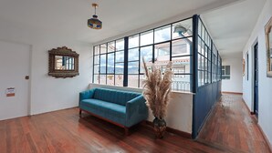 Une pièce spacieuse avec un canapé bleu, une grande fenêtre donnant sur un beau paysage et un vase décoratif contenant des plumes d’herbe des pampas.