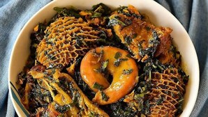 A bowl of food with leafy greens and a round orange item, possibly a vegetable or fruit. - BeamGate Hotel (Uyo)