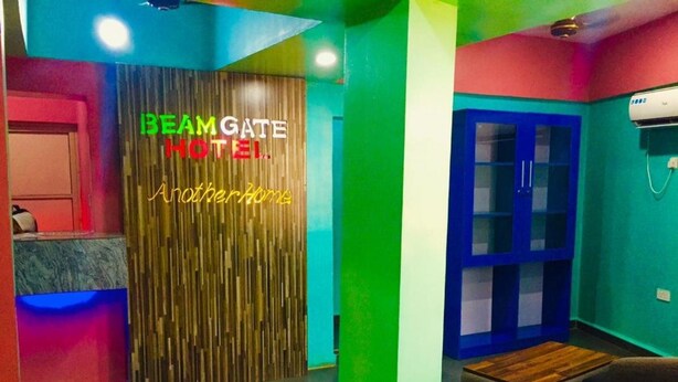 A hotel lobby with a wooden wall and a neon sign reading "BEAM GATE HOTEL Another Home". - BeamGate Hotel (Uyo)