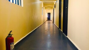 A long, narrow hallway with a fire extinguisher on the left and doors on both sides. - BeamGate Hotel (Uyo)