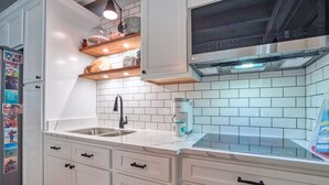 A kitchen with white cabinets, a stainless steel sink, a coffee maker, and a microwave.