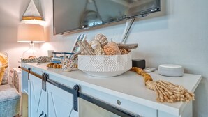 A kitchen counter with a bowl of decorative items, a television above, and a sliding door.