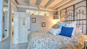 A bedroom with a bed, a door, a mirror, and a wall with a decorative metal headboard.