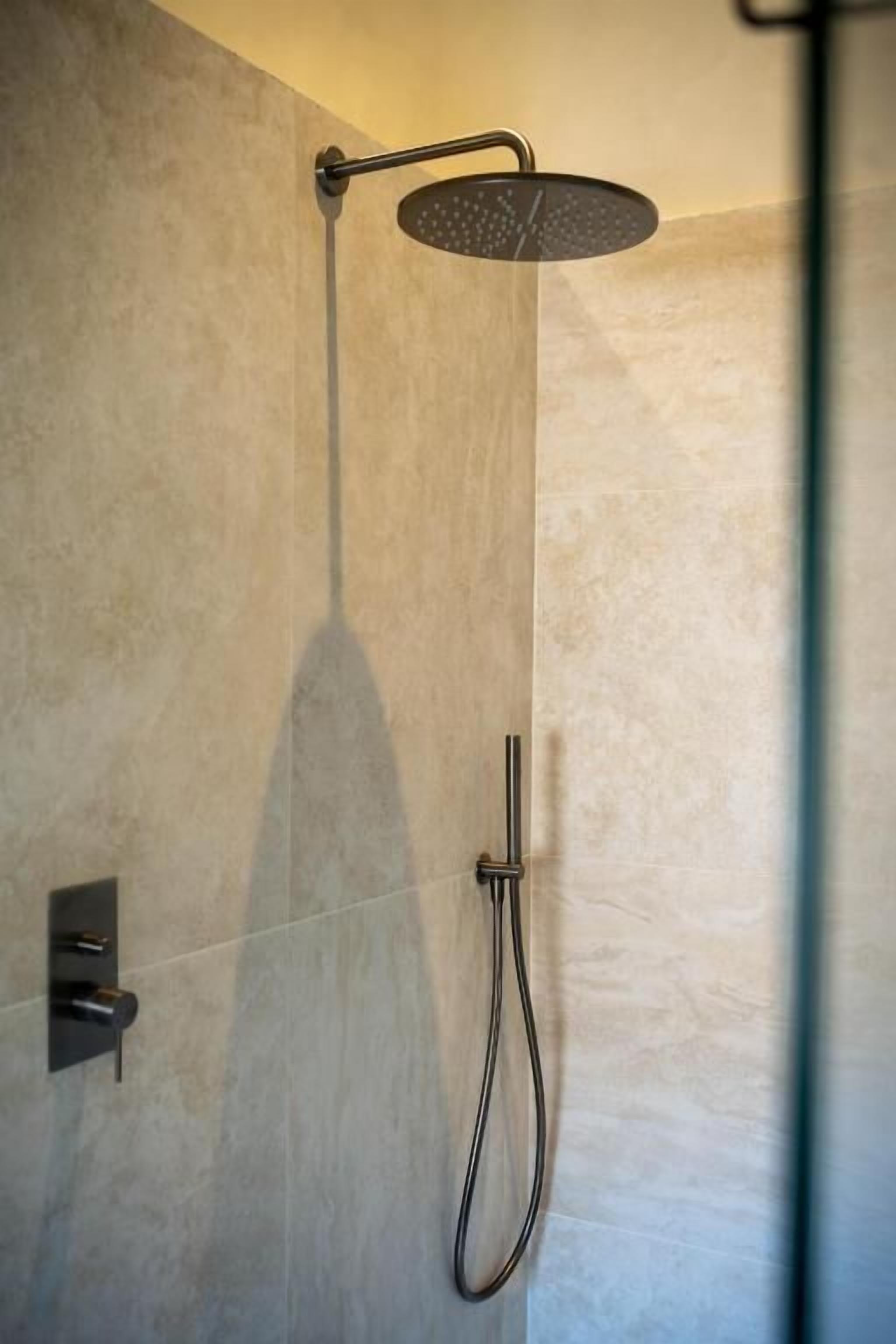 A modern shower with a handheld showerhead and a wall-mounted control panel.