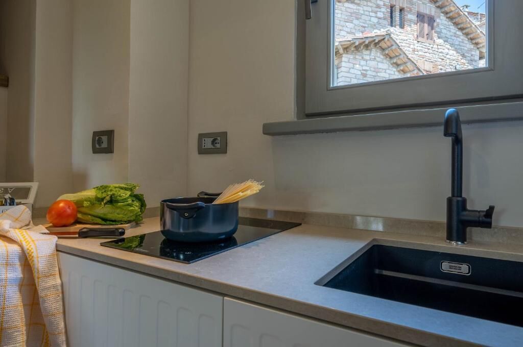 Une cuisine au design moderne, dotée d’une cuisinière intégrée, d’un évier et d’une fenêtre donnant sur des immeubles.