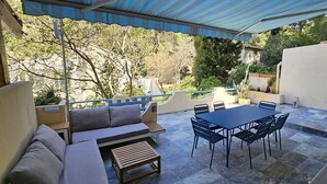 Un patio al aire libre con mesa y sillas, un sofá y un área cubierta.