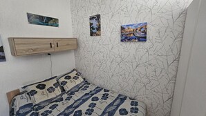 Un dormitorio con cama, cabecero de madera y tres cuadros en la pared.