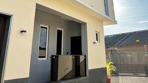A modern two-story house with a balcony, a covered porch, and a fenced backyard. - All States Apartments (Abuja)