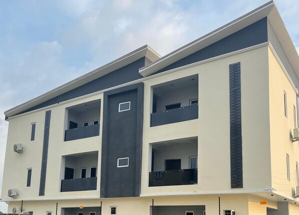 A multi-story building with balconies, a flat roof, and a light-colored facade. - All States Apartments (Abuja)