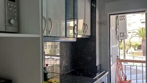 A kitchen with a microwave, cabinets, and a stove. - Salomar Golf+parking+piscina+tenis (Salobreña)