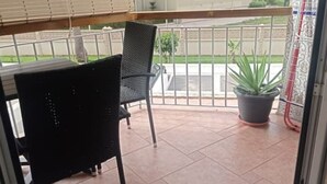 A balcony with a chair, a potted plant, and a view of a street. - Salomar Golf+parking+piscina+tenis (Salobreña)