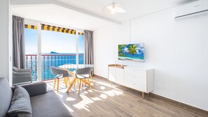 Enjoy a sea view from the large window in this stylish living room, featuring a sofa, dining table, and flat-screen TV.