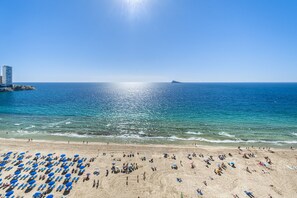 A beach with rows of blue umbrellas and people sunbathing. - Las Damas 12-E Levante Beach (Benidorm)