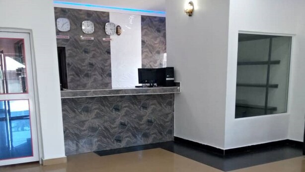 A modern reception area with a marble counter, wall clocks, and a large window.