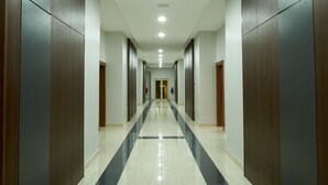 A long, narrow hallway with a tiled floor and wooden paneling on the walls. - Arcade Sinclair (Abuja)