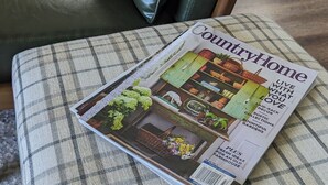 Eine Zeitschrift auf einem karierten Kissen auf einem Stuhl.