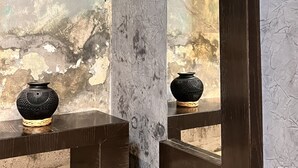 A bathroom with a textured wall, a wooden ceiling, and a dark wooden vanity with two black vases. - Beautiful studio in Jalatlaco, a beautiful neighborhood (Oaxaca de Juárez)