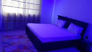 A bedroom with a bed, nightstands, a rug, and curtains.