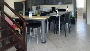 Ett modernt kök med mörka skåp, en köksö och en trappa som leder till ett annat plan.