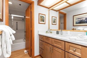 A bathroom with a shower, a sink with toiletries, and a large mirror. - Ridgepoint 3 Bedrooms RGT-117 by KBM (Park City)