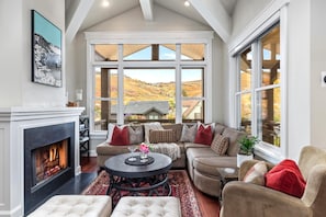 A cozy living room with a fireplace, large windows offering a scenic view, and comfortable seating. - Red Crest 3 Bedrooms PWS-957 by KBM (Park City)