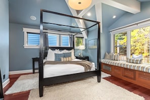 A bedroom with a four-poster bed, a nightstand, a bench with cushions, and a large window with a view of trees. - Red Crest 3 Bedrooms PWS-957 by KBM (Park City)