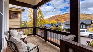 A covered porch with stone flooring, outdoor seating, and a view of a hillside town. - Red Crest 3 Bedrooms PWS-957 by KBM (Park City)