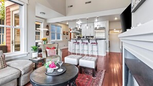 A spacious living area with a fireplace, a dining table with chairs, a kitchen with bar stools, and a large window. - Red Crest 3 Bedrooms PWS-957 by KBM (Park City)