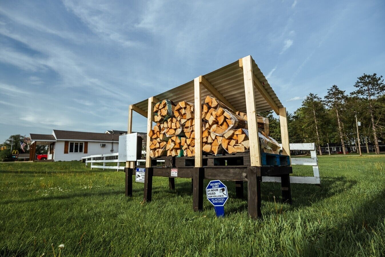 A wooden structure with a roof, surrounded by a grassy field, and a security alert sign.