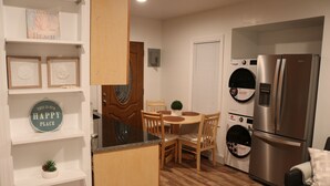 Une cuisine compacte équipée d’un réfrigérateur, d’un lave-linge, d’une table à manger et de chaises.
