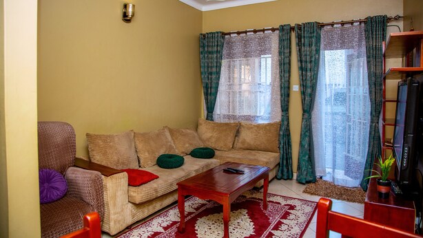A living room with a sofa, a coffee table, a television, and a bookshelf. - Beautiful 2-bed House in Kampala (Kampala)