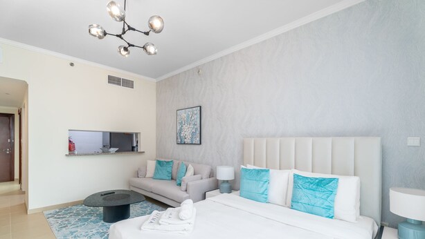 Ein modernes Hotelzimmer mit einem großen Bett, einer Sitzecke, einem kleinen Tisch und einem an der Wand befestigten Fernseher.