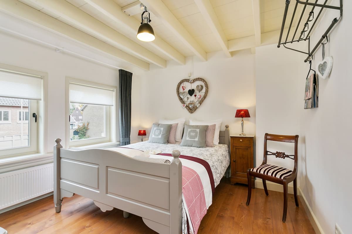 Ein Schlafzimmer mit Bett, Stuhl, einer herzförmigen Dekoration und einem Fenster.