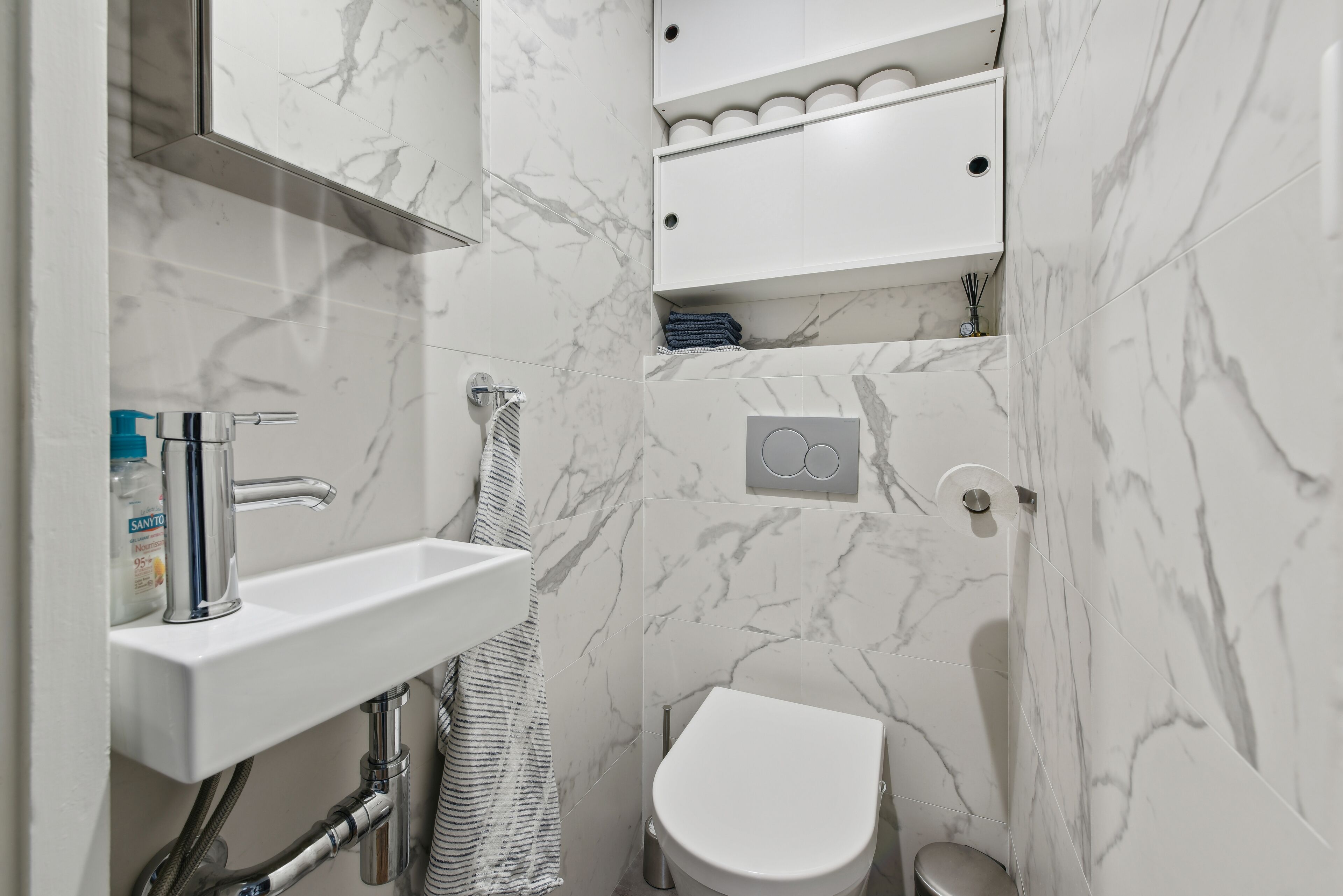Ein Badezimmer mit einem weißen Waschbecken, einer Toilette und einem Handtuchhalter.