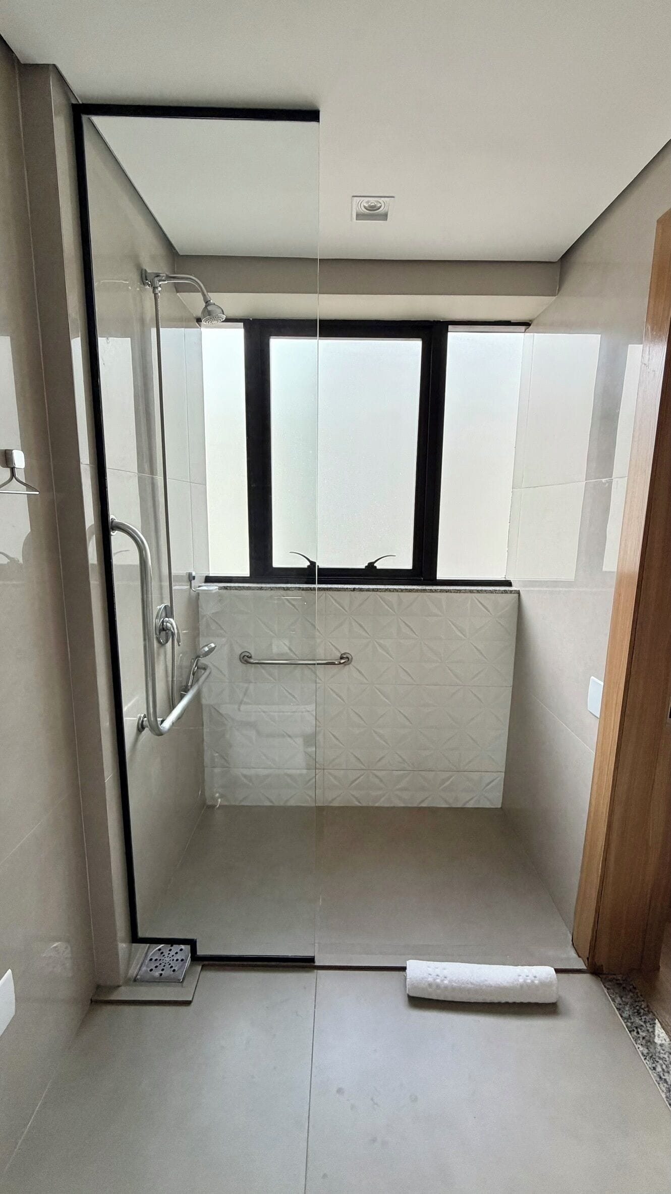 Un baño moderno con cabina de ducha de vidrio, ventana y retrete.