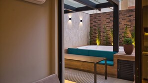An outdoor seating area with a wooden table and benches, a brick wall, and a potted plant. - Life Residence (Belo Horizonte)