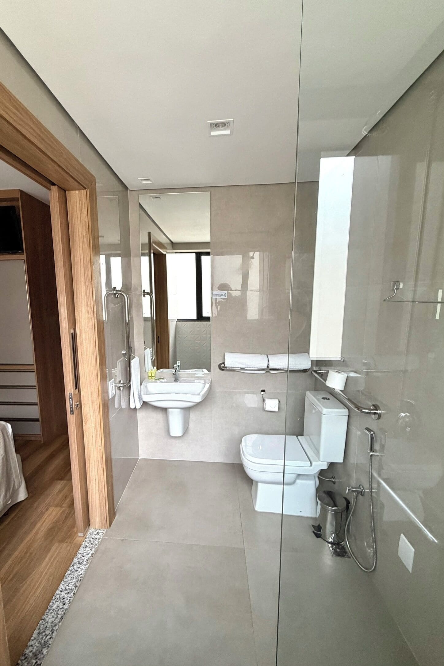 Een moderne badkamer met een douchecabine van glas, een toilet en een wastafel.